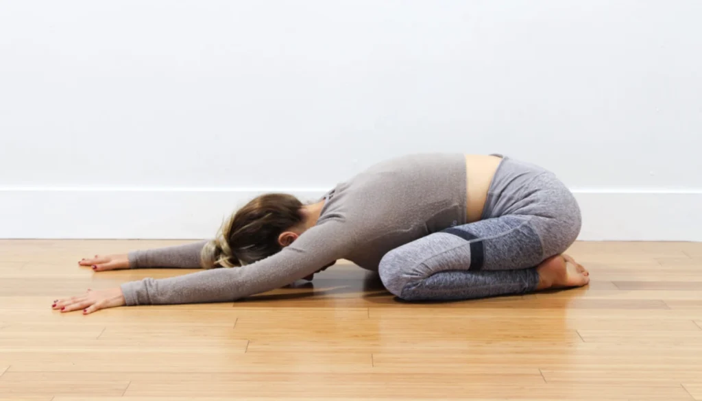 A lady performs a Child’s Pose (Balasana – Wide Knees)