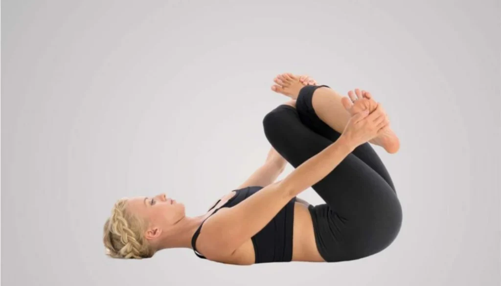 A lady performs a Reclining Cow Face Pose (Supta Gomukhasana)