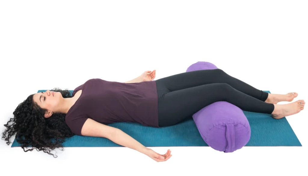 A lady performs a Resting Pose (Salamba Savasana)