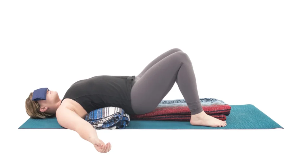 A lady laying on the floor and performs a Supported Bridge (Salamba Setu Bandha)