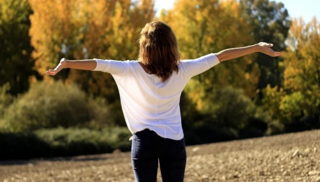 A lady stands in the garden and performs a rest and reflect pose