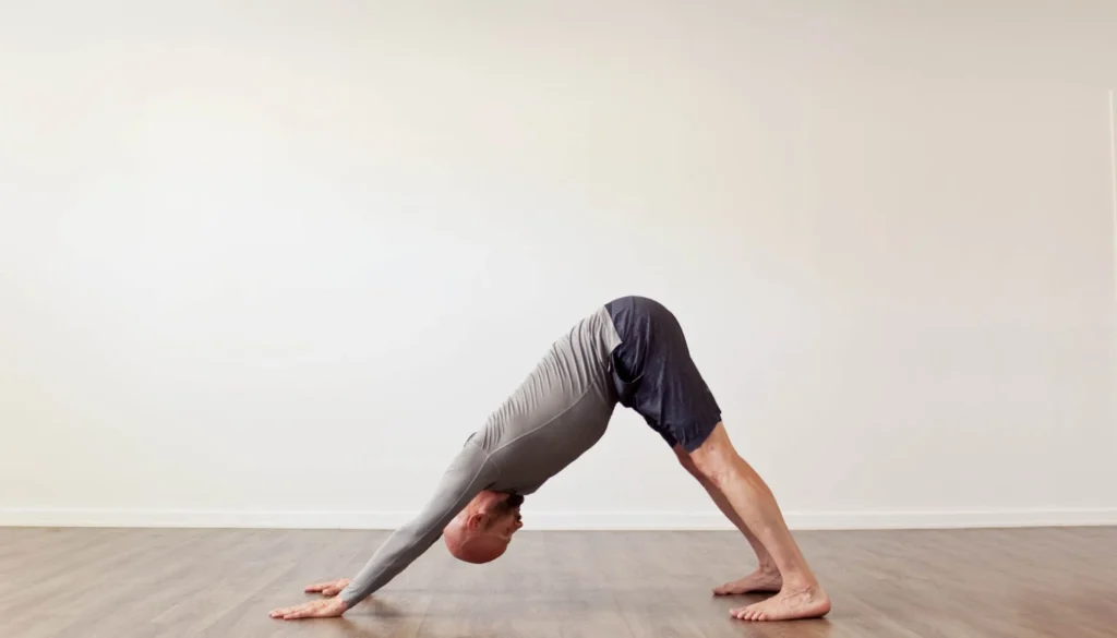 A man performs a Downward-Facing Dog (Adho Mukha Svanasana)